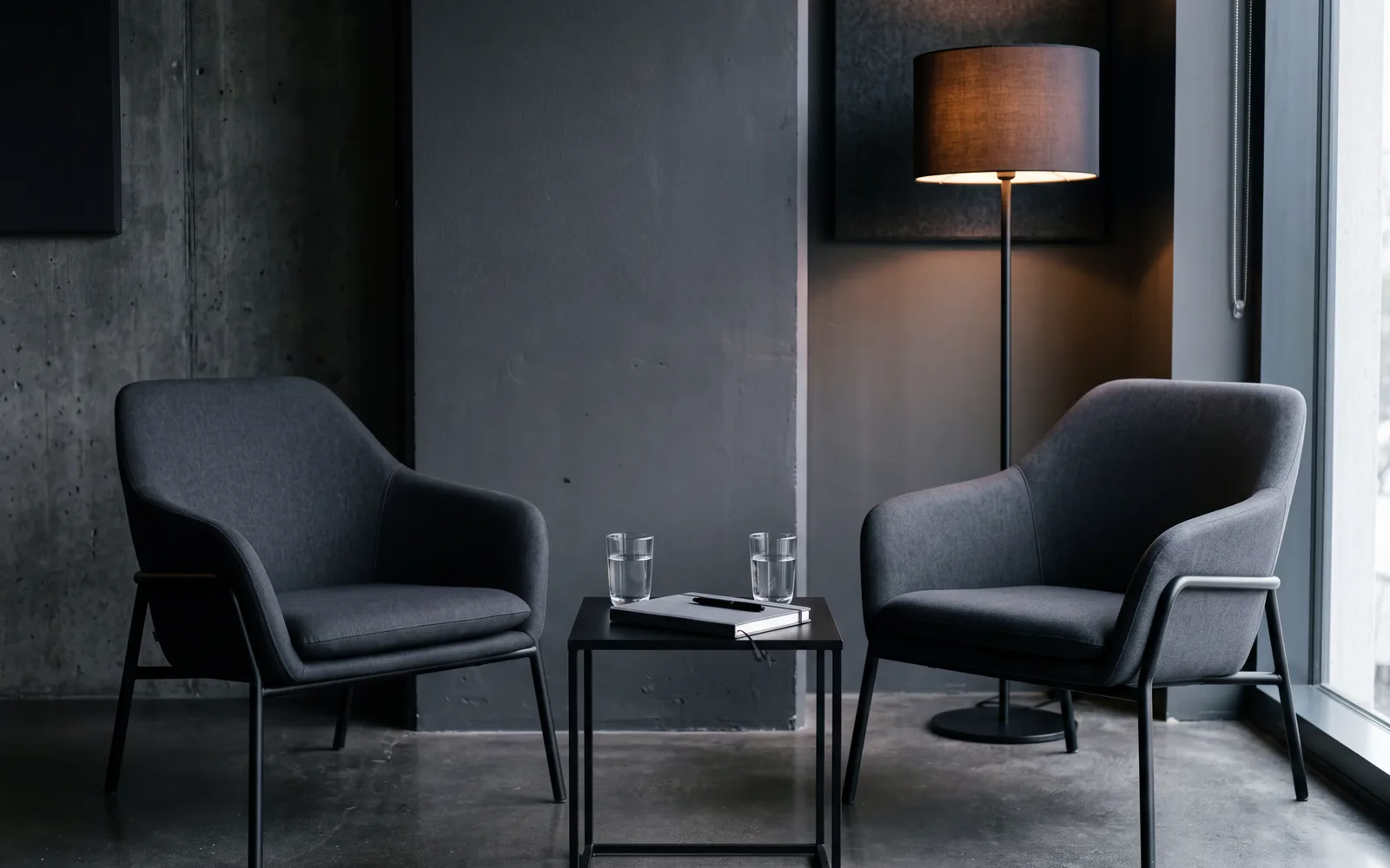 A quiet corner for a first conversation: two armchairs facing each other, a low table with two glasses of water between them