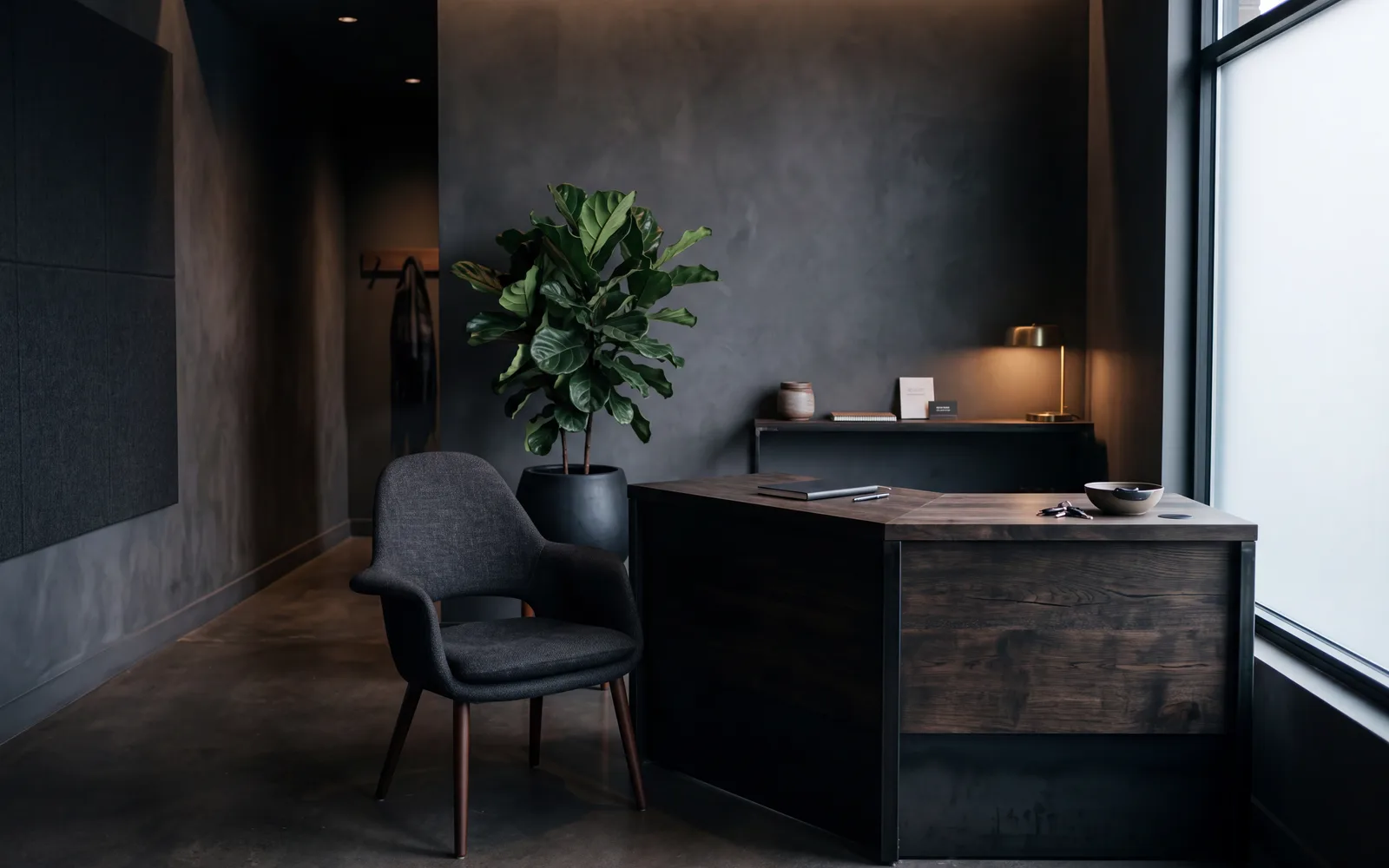 Reception area of a small business: a low counter of wood and metal, a chair beside it, warm light